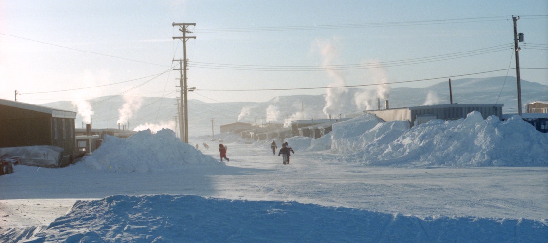 At least four students in the distance can be seen walking home at noon on an extremely cold winter day.